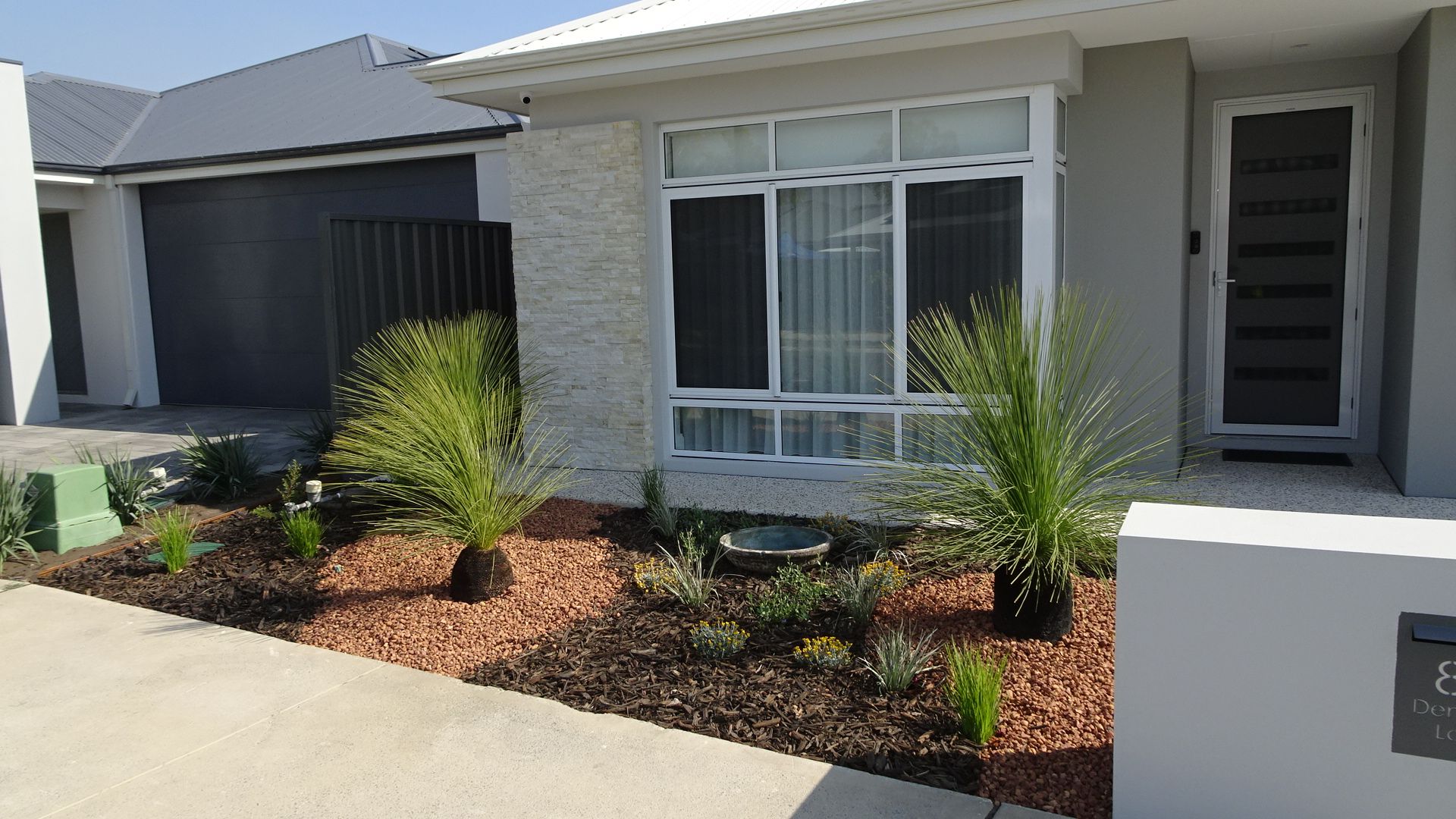Front view of a house with a gravel garden bed and greenery.