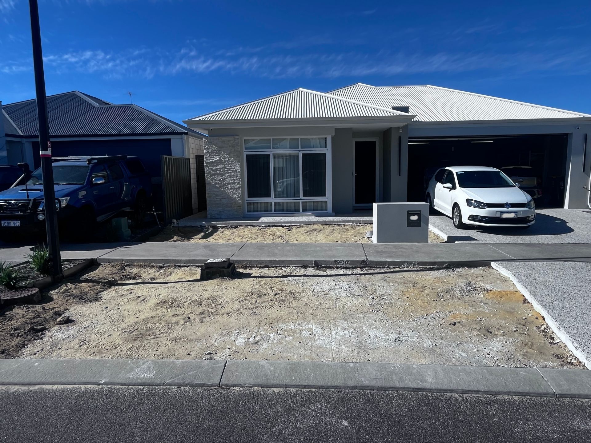 A suburban house with a car parked in the driveway and a partially landscaped front yard.
