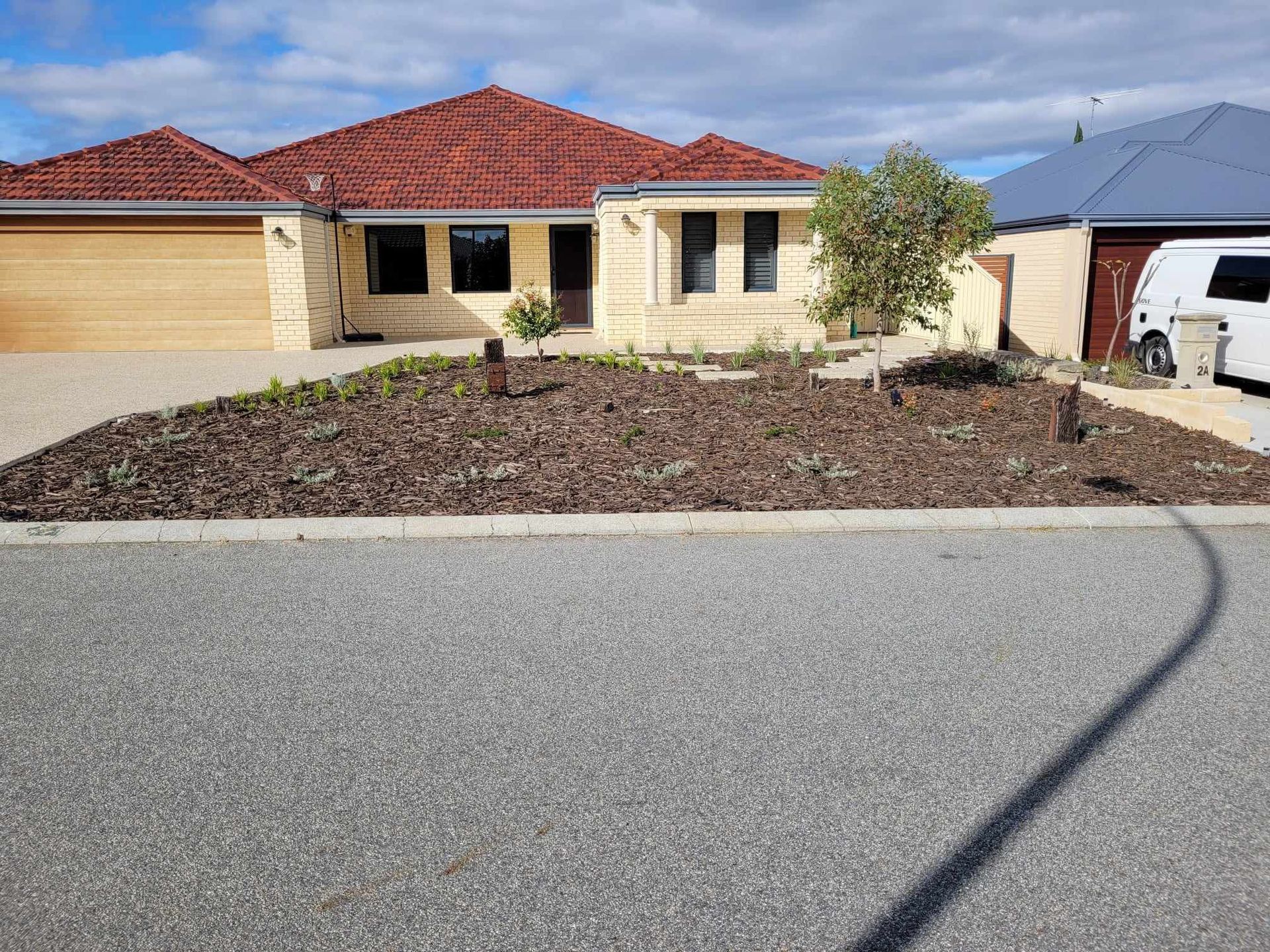 Beige house with a gravel driveway and mulch garden bed.