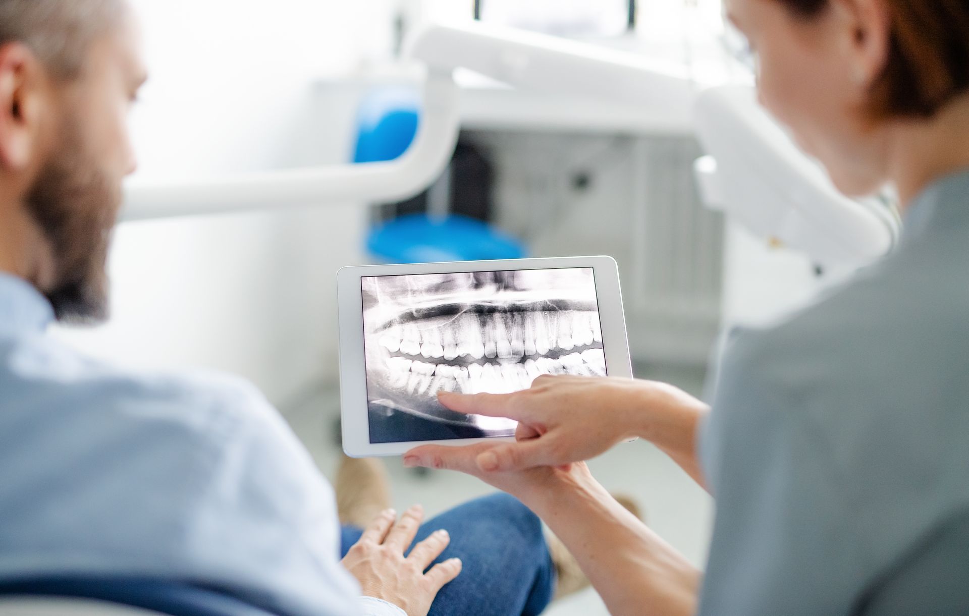 A dentist performs an annual check-up on a male patient in a dental surgery.