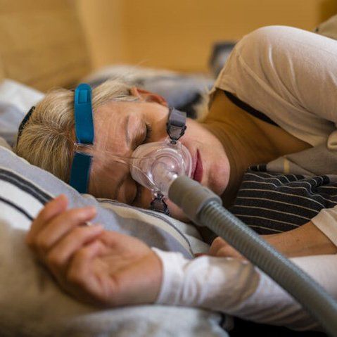 Person sleeping with a CPAP mask on in bed.