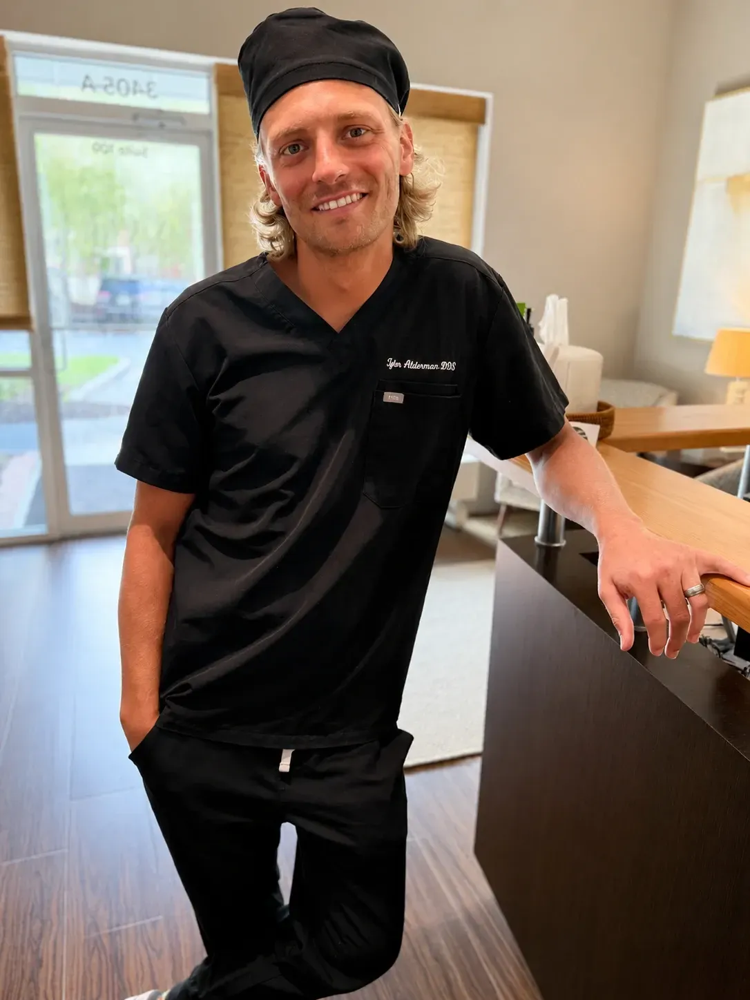 Dentist wearing surgical loupes and mask, focused on work, medical setting.