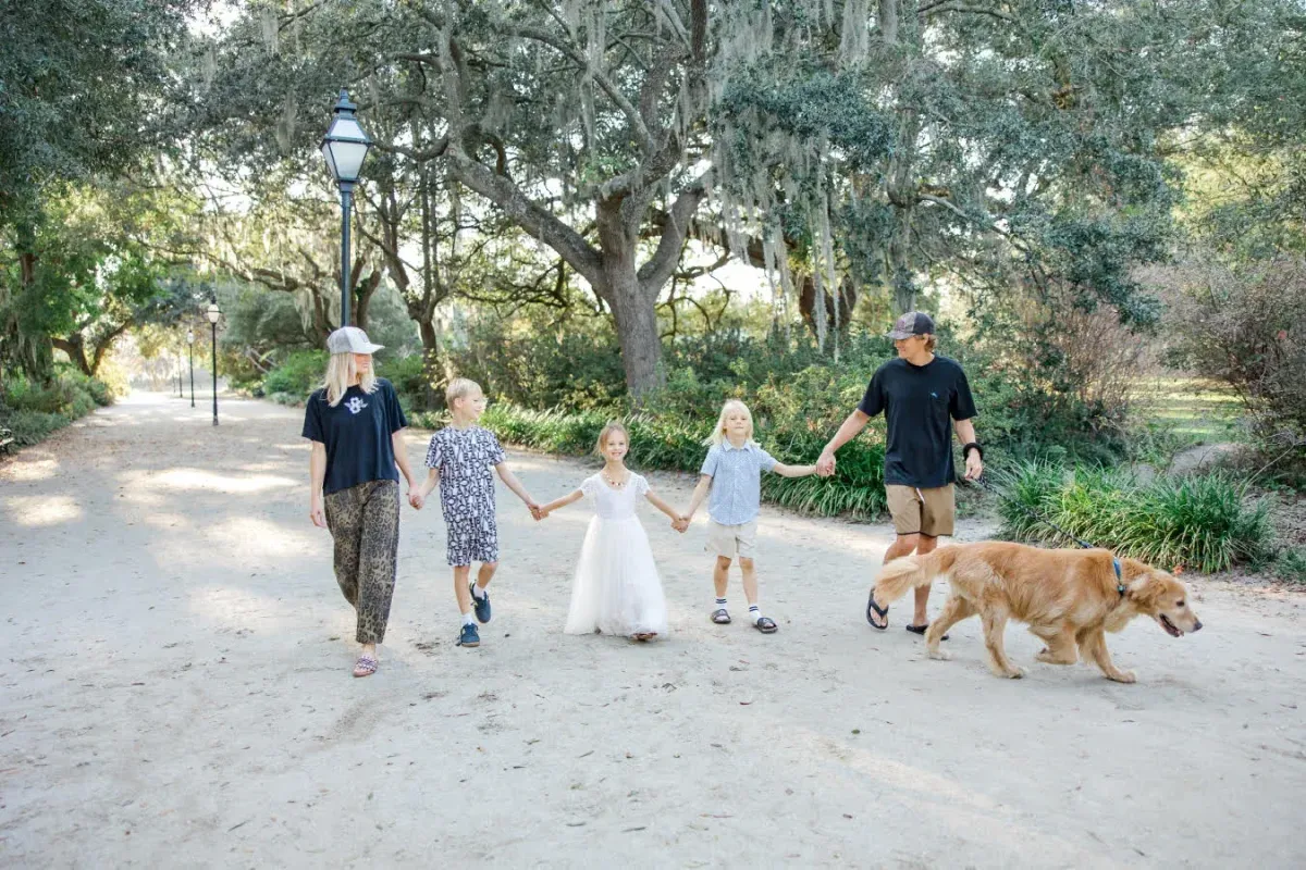 Family walking together with their golden retriever beneath oak trees in Mount Pleasant, South Carolina.