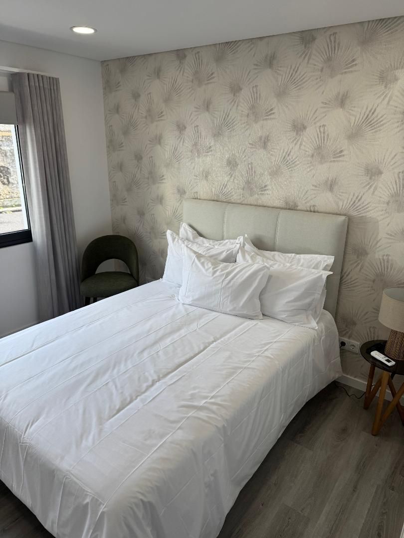 A bedroom with a bed , chair , lamp and window.