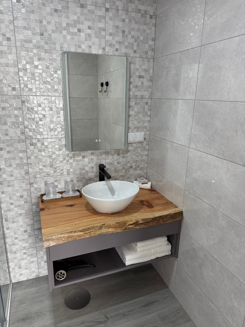 A bathroom with a wooden vanity , sink , mirror and towels.