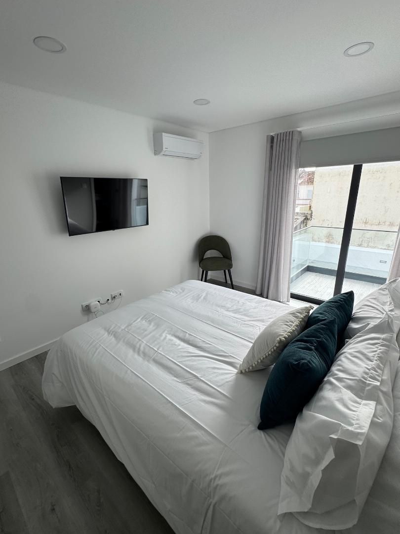A bedroom with a large bed and a flat screen tv on the wall.