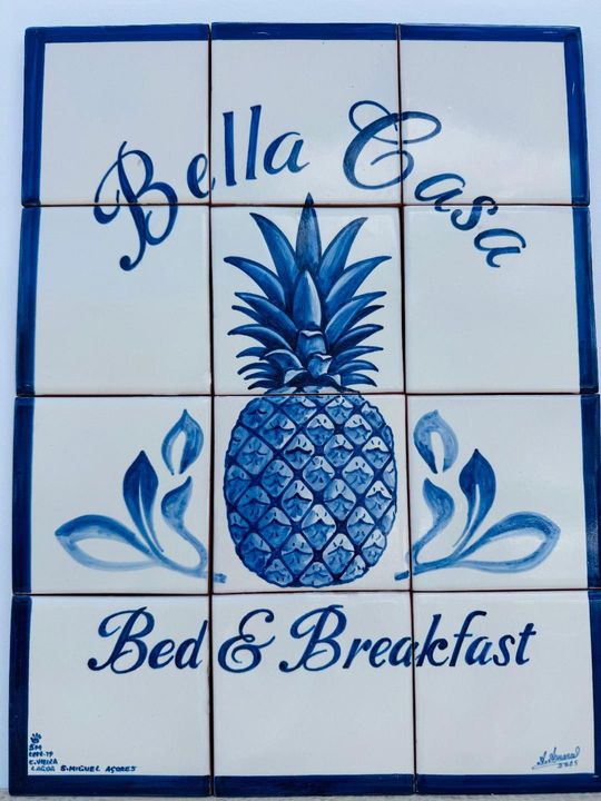 A blue and white decorative tile mural of a pineapple with the text 