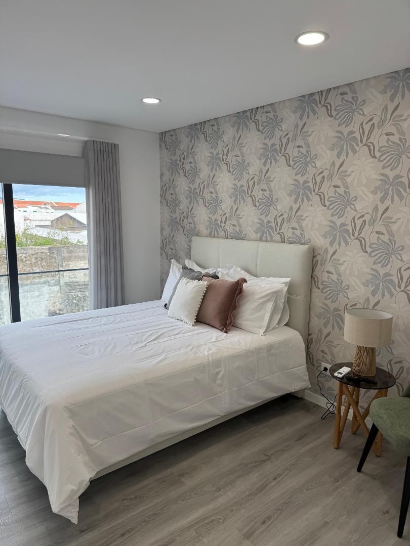 A bedroom with a large bed , a lamp , and a window.