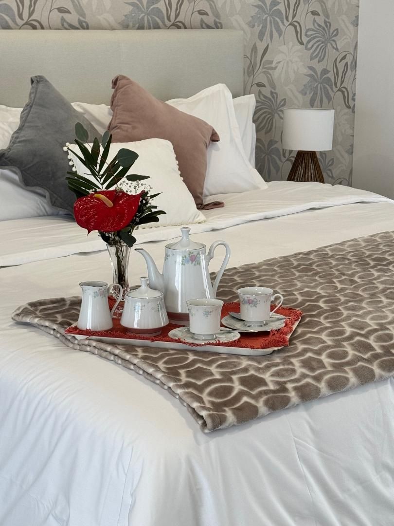 A bed with a tray of tea and coffee on it