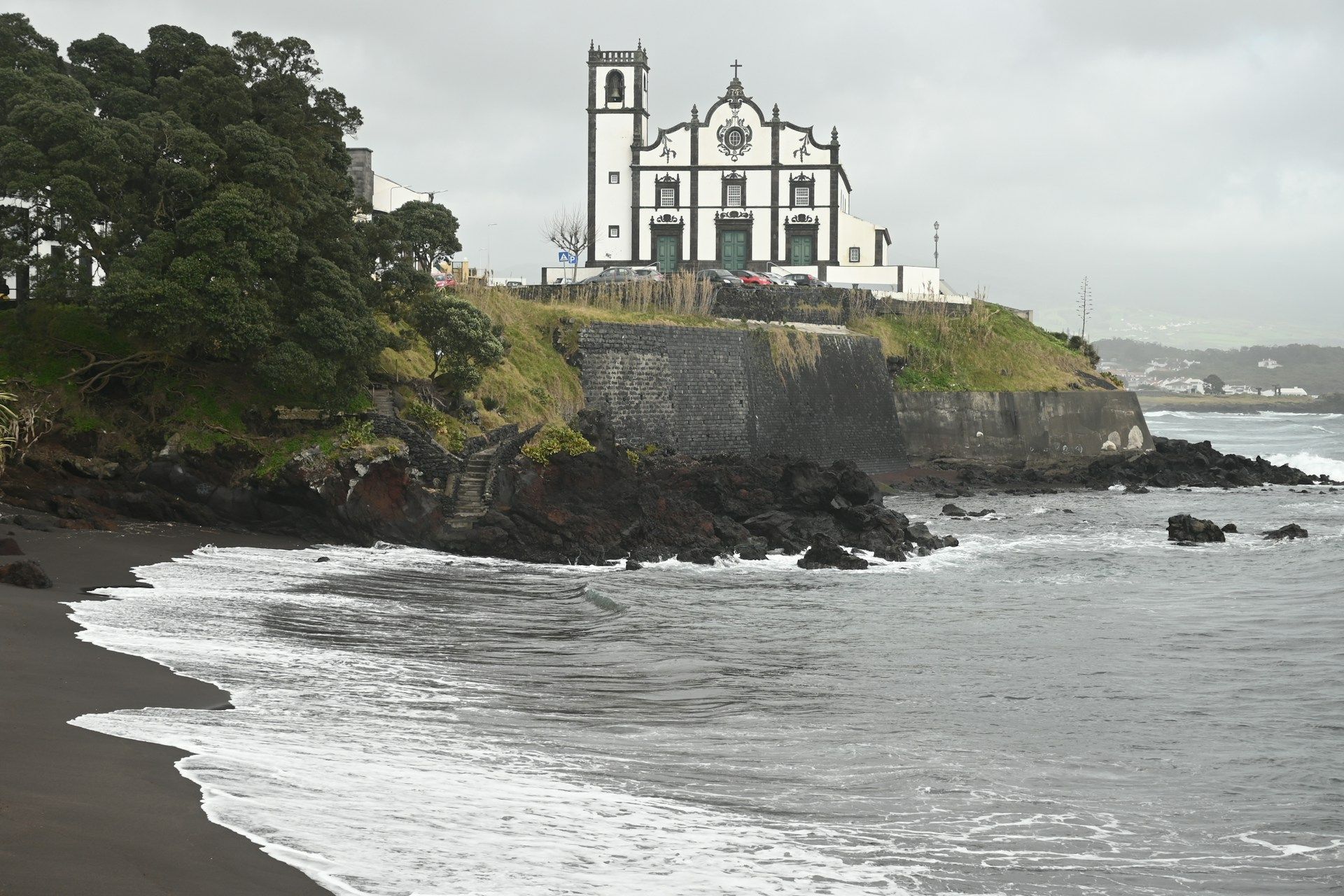 A church sits on top of a cliff overlooking the ocean