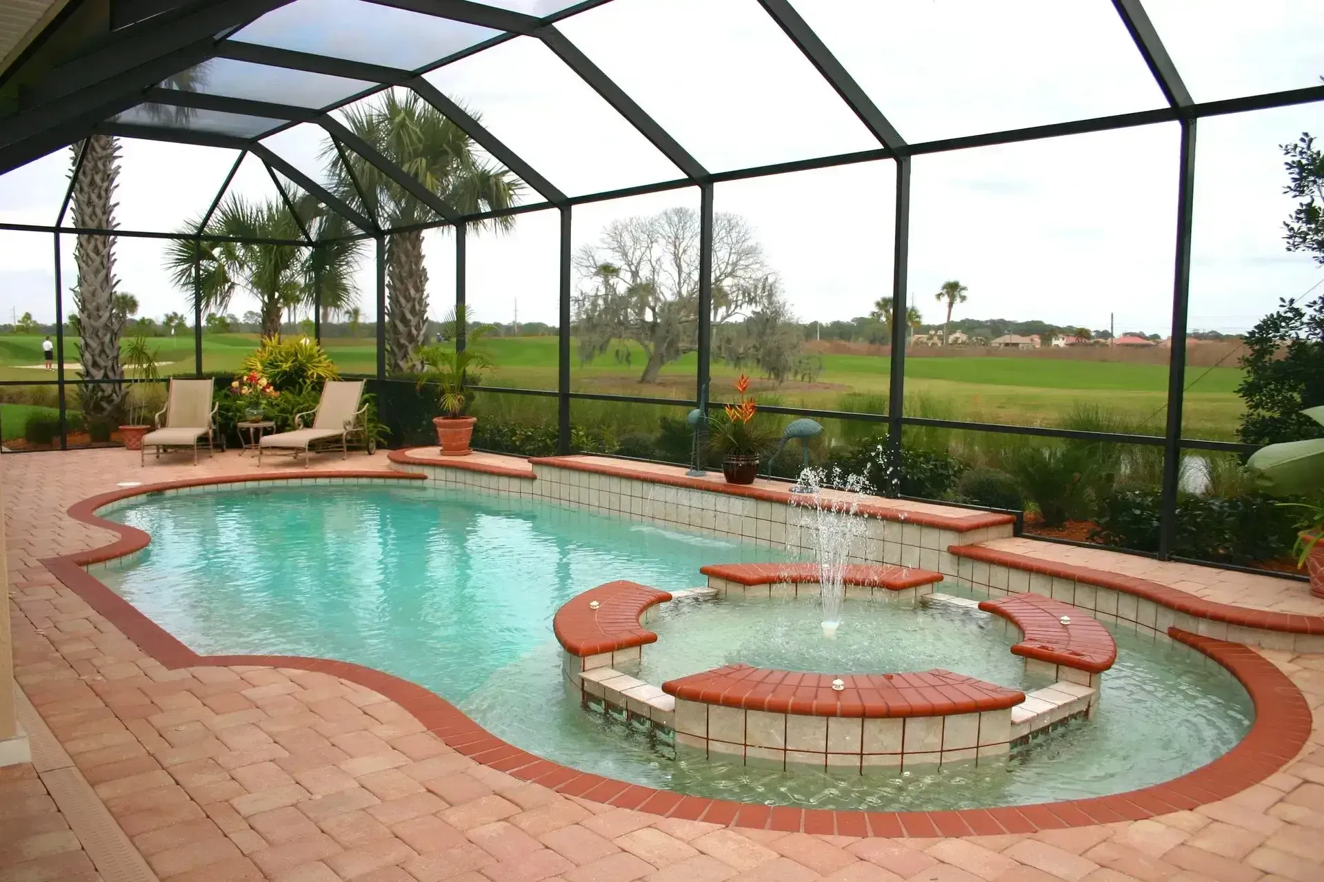 A screened-in patio features a swimming pool with a circular spa and fountain, surrounded by pavers and a golf course view.
