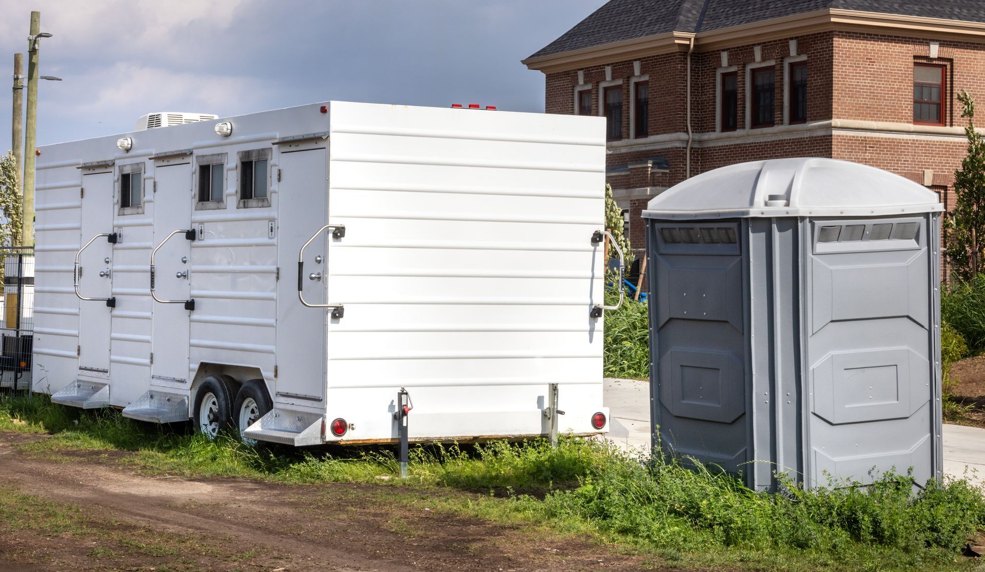 A side-by-side comparison of a basic portable toilet unit and a luxury restroom trailer for events