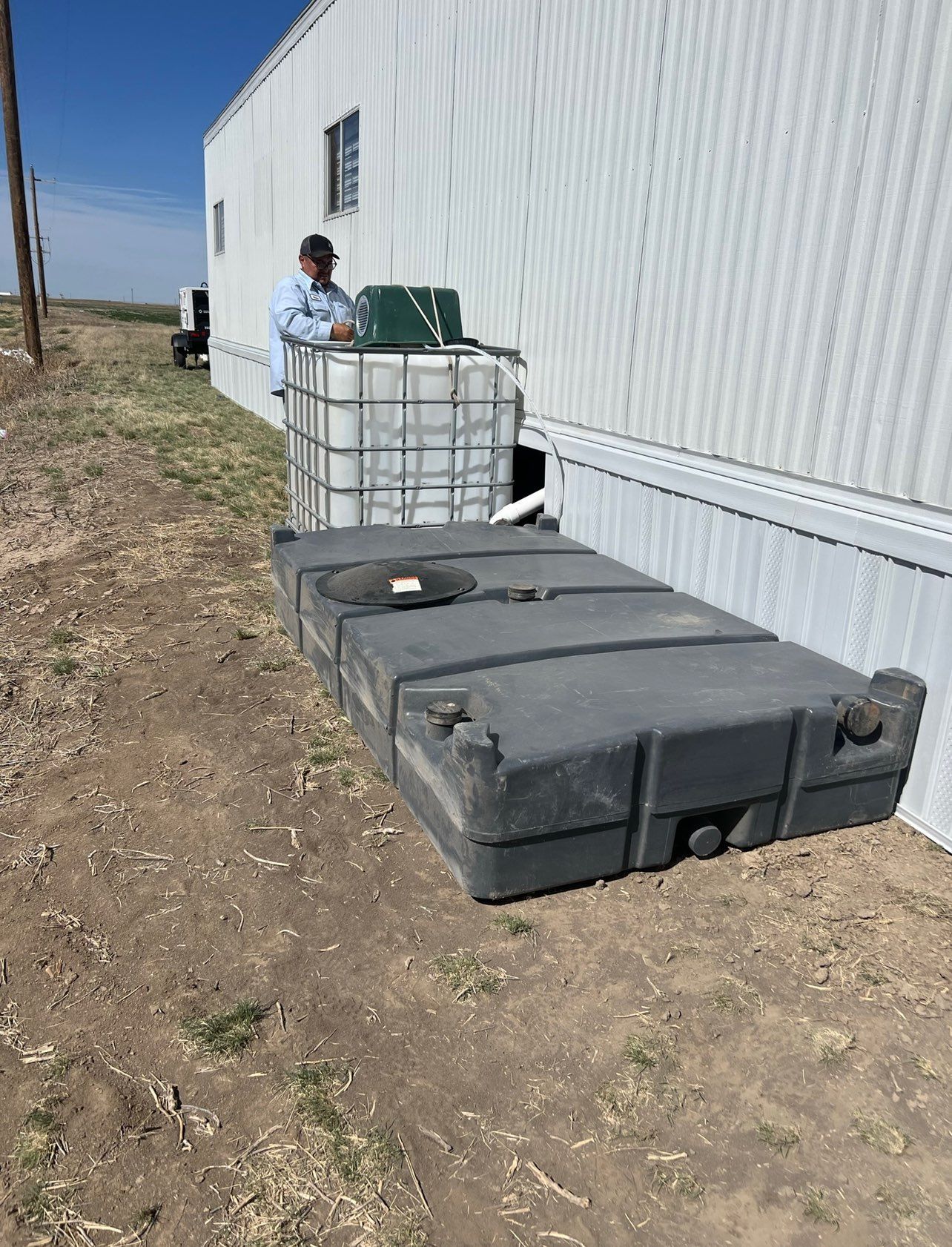 Man near a white building with a water storage system including tanks.