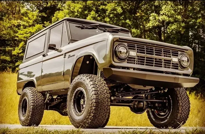 A black ford bronco is parked on the side of the road.