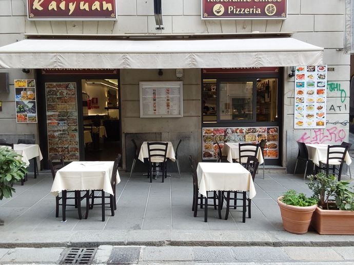 Un ristorante con tavoli e sedie all'esterno e un cartello che dice pizzeria