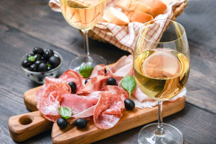 Un tagliere di legno con sopra carne e bicchieri di vino su un tavolo di legno.