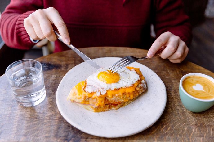 Una persona è seduta a un tavolo con un piatto di cibo e una tazza di caffè.