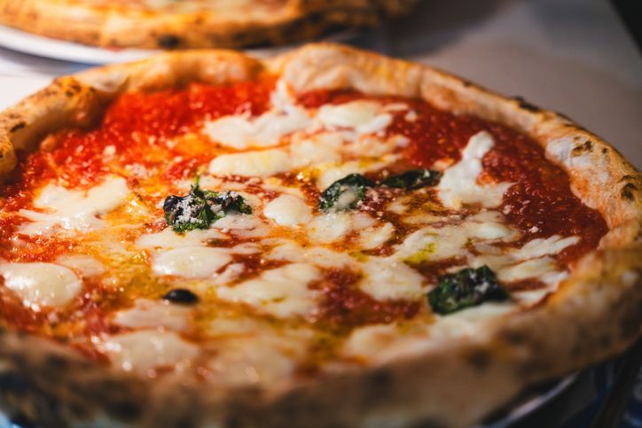 Una pizza con salsa di pomodoro e formaggio è appoggiata su un tavolo.