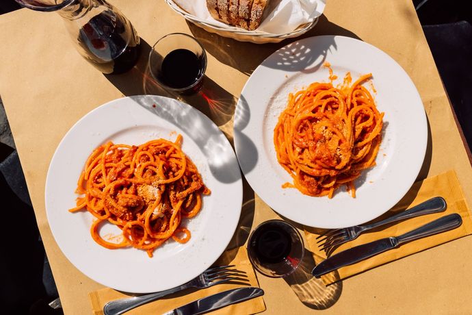 Due piatti di spaghetti e un bicchiere di vino su un tavolo.