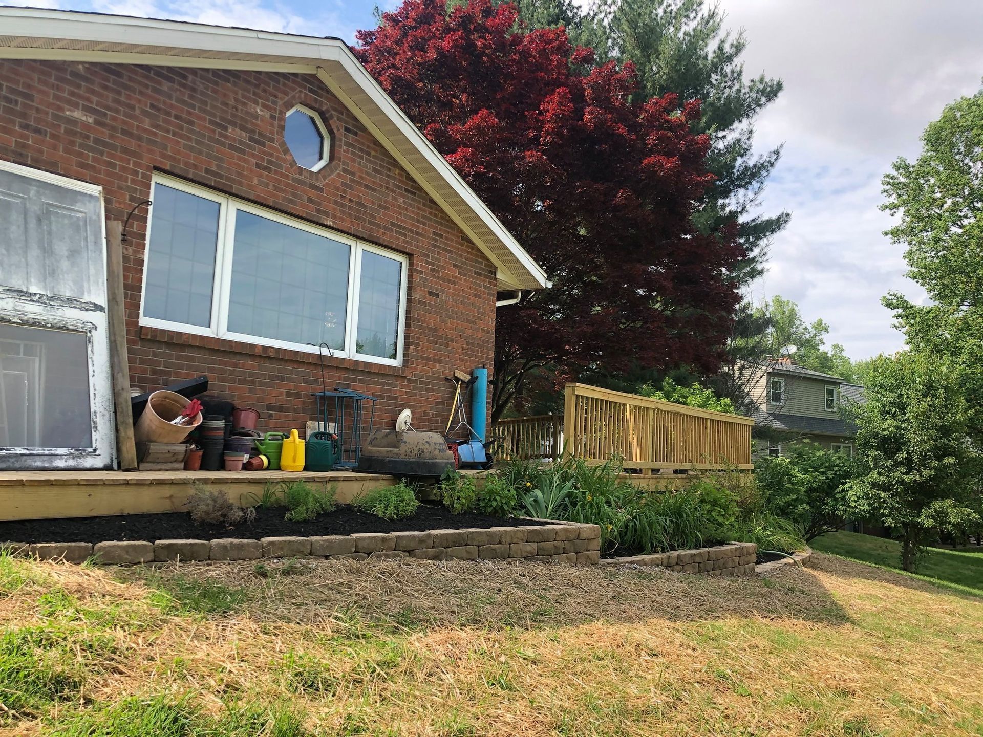 Brick house with large windows, raised garden beds, and a flowering tree in the yard.