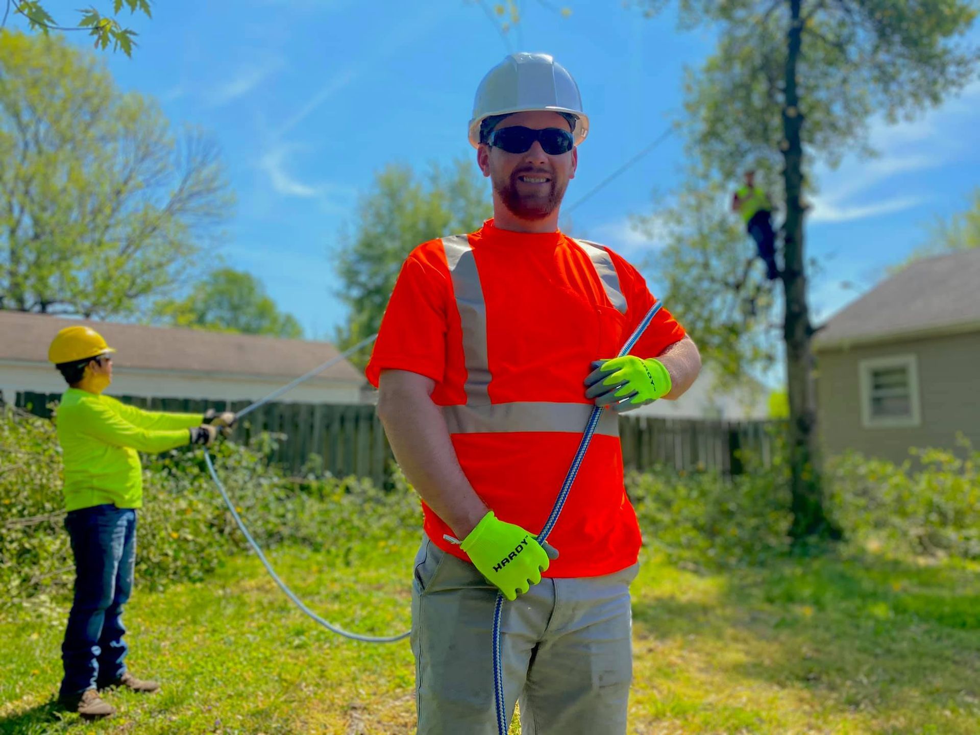 Two utility workers in safety gear inspecting a grassy yard with a cable line between them