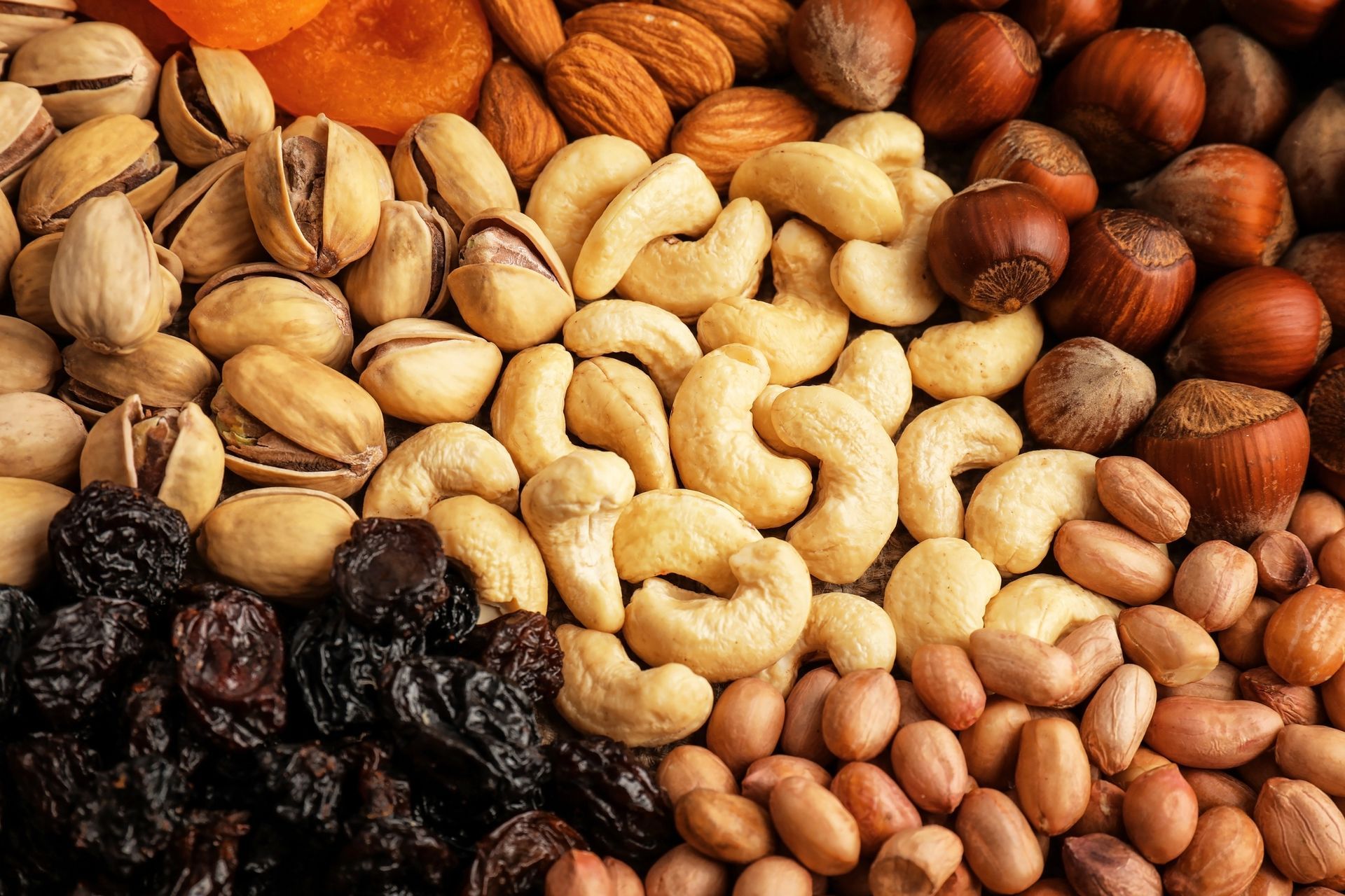 Primer plano de frutos secos y nueces, incluidos pistachos, anacardos, almendras y cacahuetes.