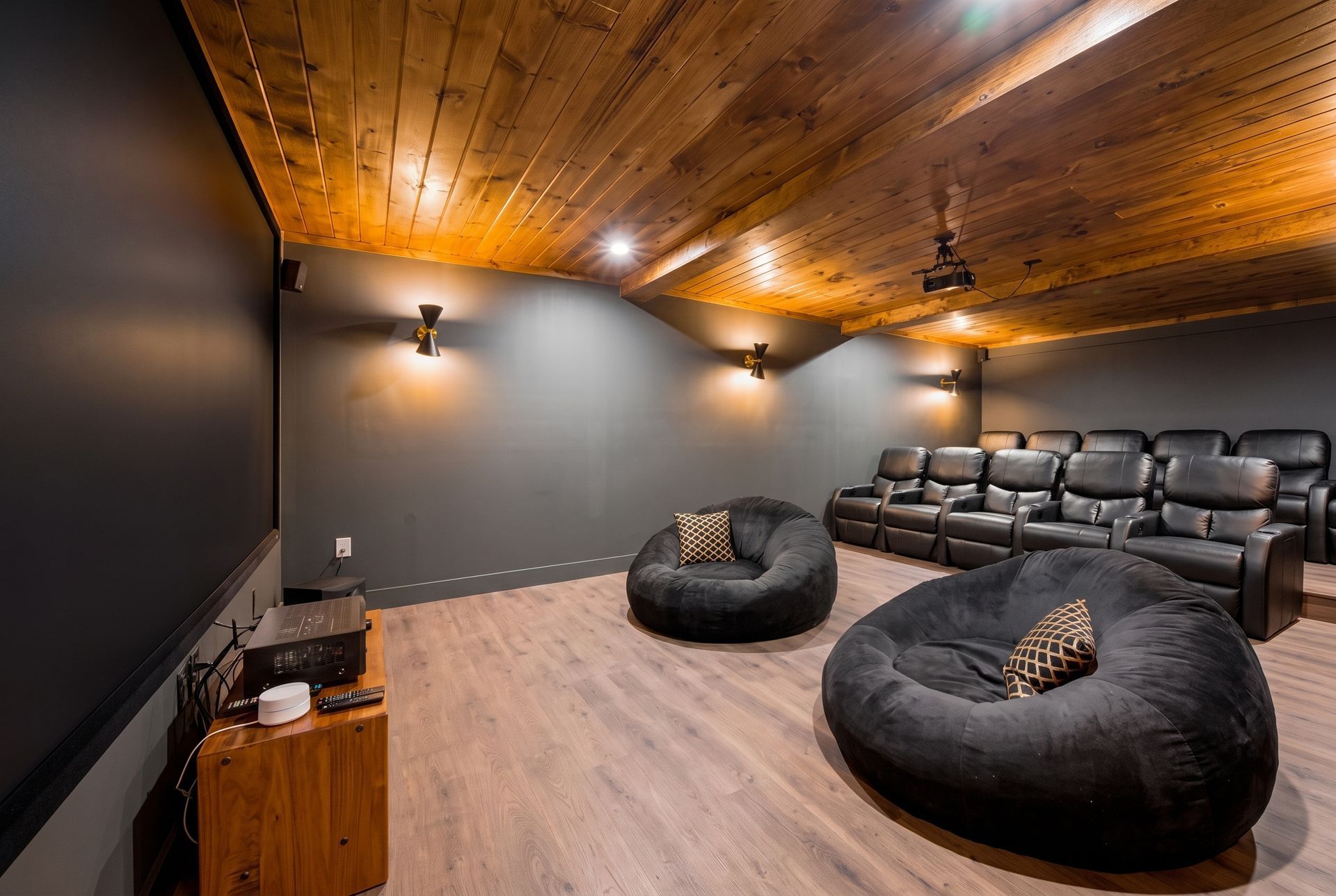 Home theater room with leather sectional, bean bags, wood ceiling, and wall sconces