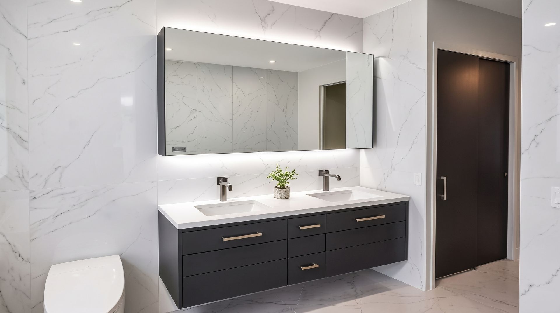 Modern bathroom with double vanity, large mirror, white marble walls, and dark cabinetry.