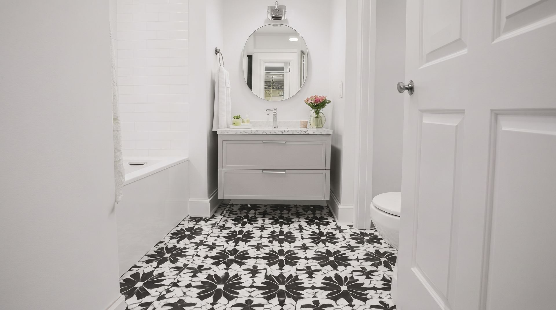 Bright white bathroom with black-and-white patterned floor, vanity mirror, and sink.