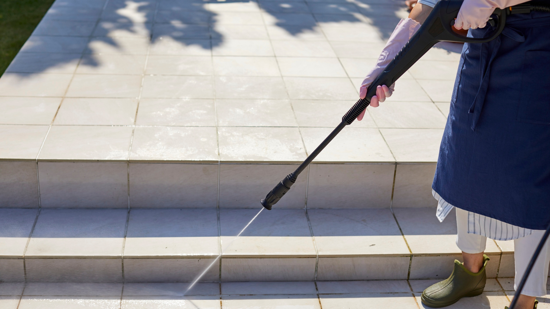 Person using a long pole to clean or inspect stone steps in bright sunlight
