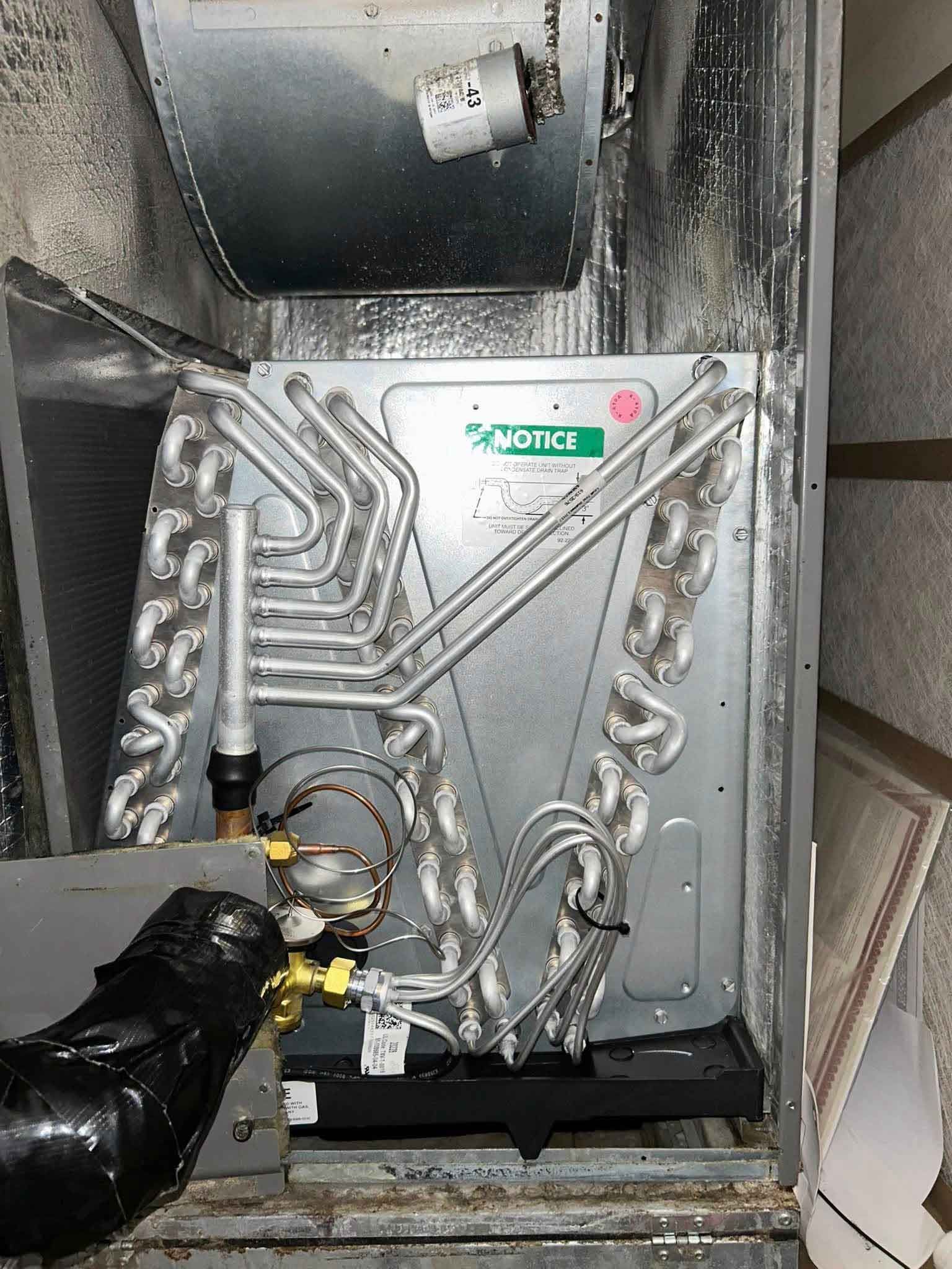 Engine compartment with metal tubing and a gloved hand holding a yellow tool or valve assembly.