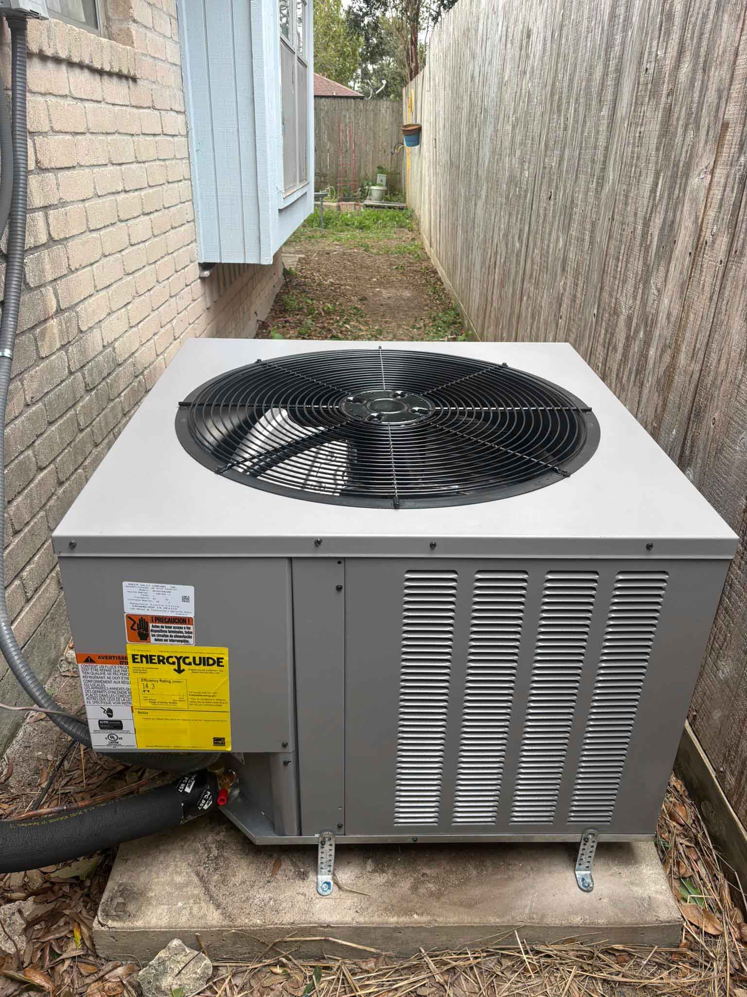 Outdoor HVAC unit beside a brick house in a narrow side yard