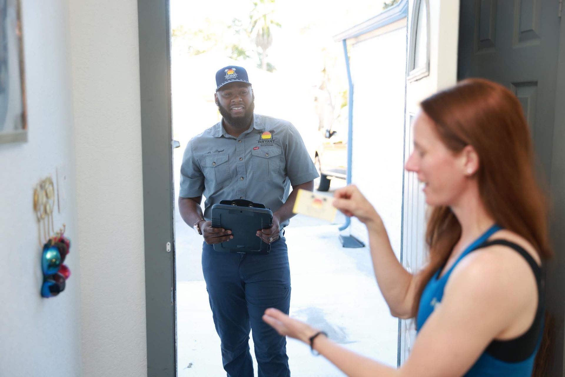 Delivery driver at a doorway handing a package to a woman in a blue top Delivery driver at a doorway handing a package to a woman in a blue top
