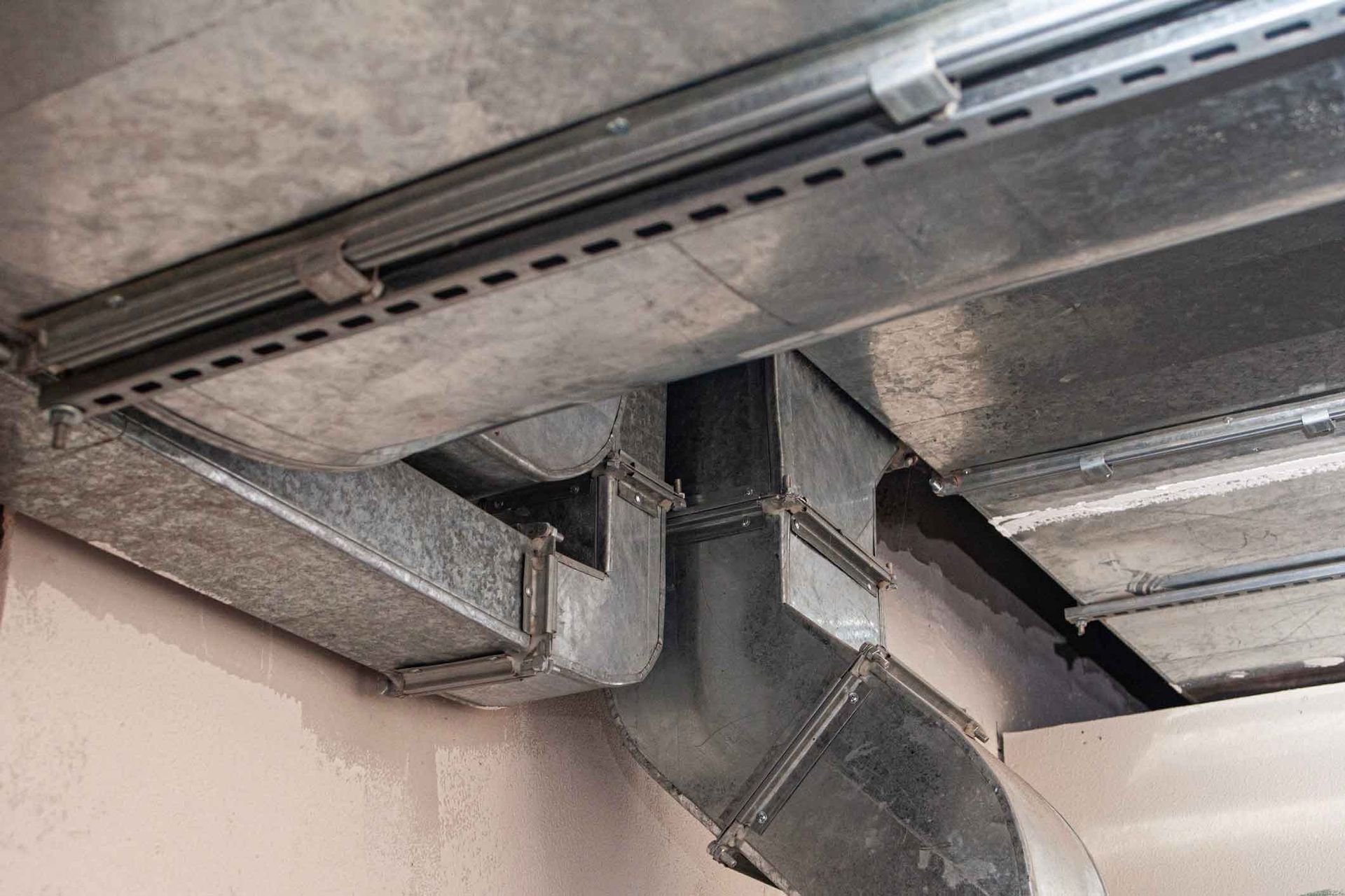 Exposed metal HVAC ducting and vents on a concrete ceiling inside a building