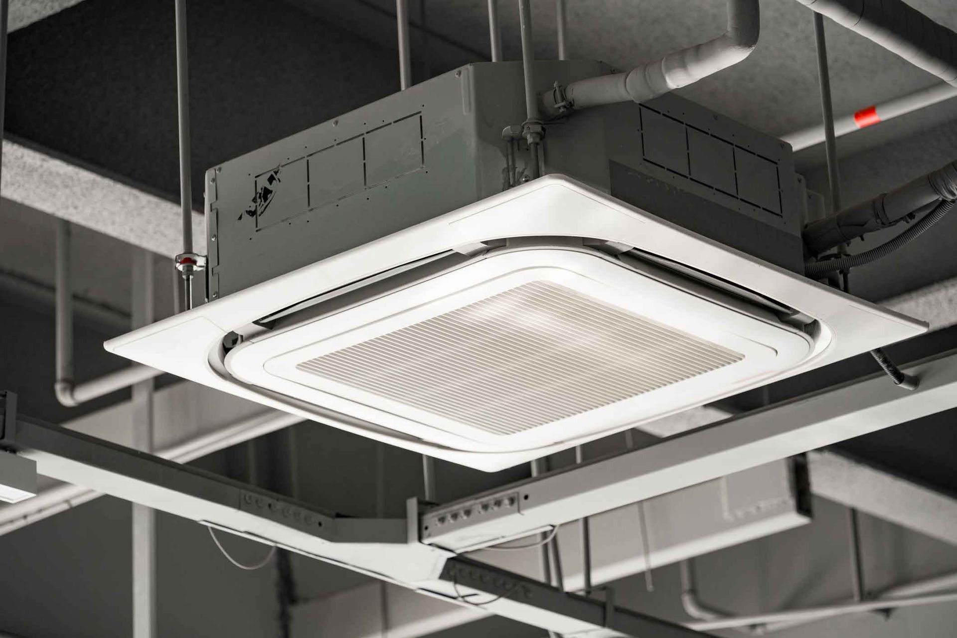 Ceiling-mounted HVAC air vent in an industrial interior with exposed ducts and beams