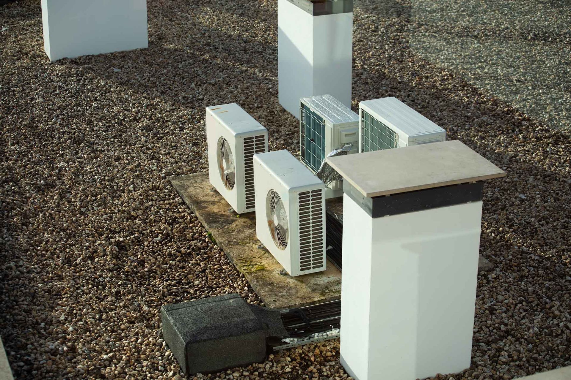 Outdoor HVAC units and electrical boxes on gravel beside a building wall Outdoor HVAC units and electrical boxes on gravel beside a building wall