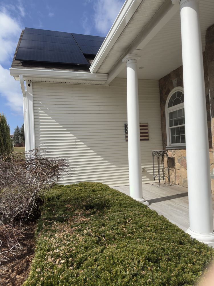 House entrance with white columns, porch chairs, and solar panels on the roof.