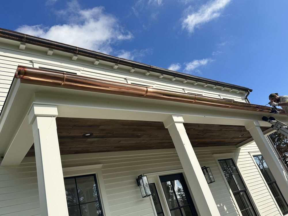 Front porch with white columns and siding under repair against a blue sky