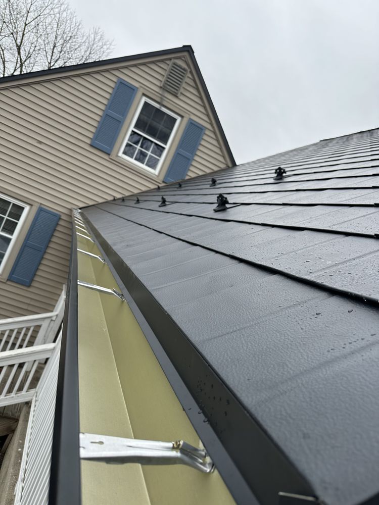 Roof and dormer with blue shutters on a beige house, viewed from below on a cloudy day