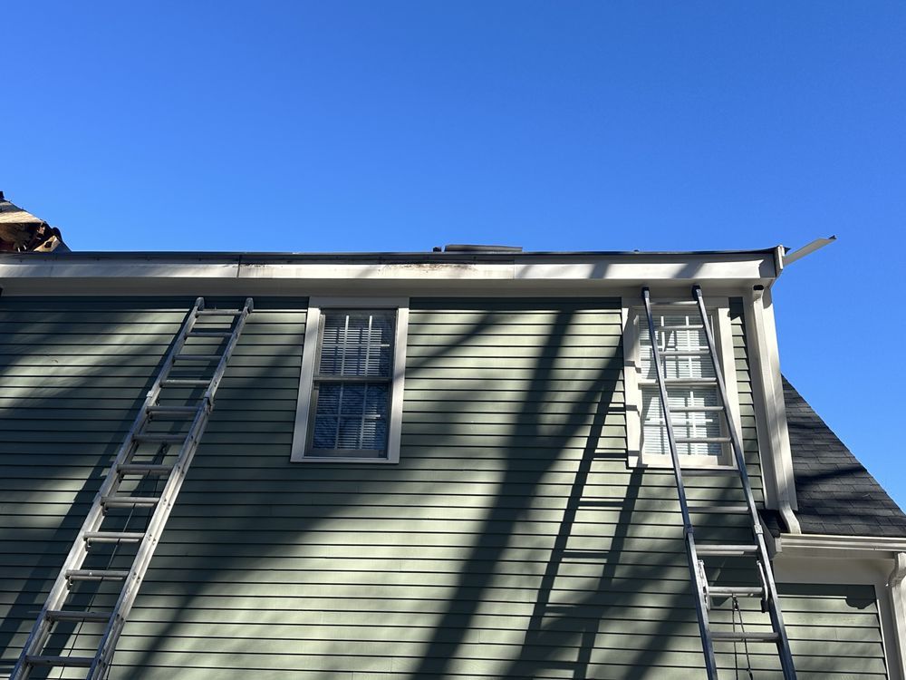 House siding with two ladders leaning against it under a clear blue sky