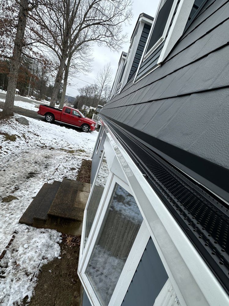 Snowy suburban house side with white-trim windows and a red pickup truck in the driveway.
