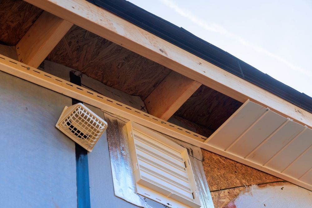 Close-up of house eaves with wooden soffit, white vent, blue wall, and a hanging light fixture