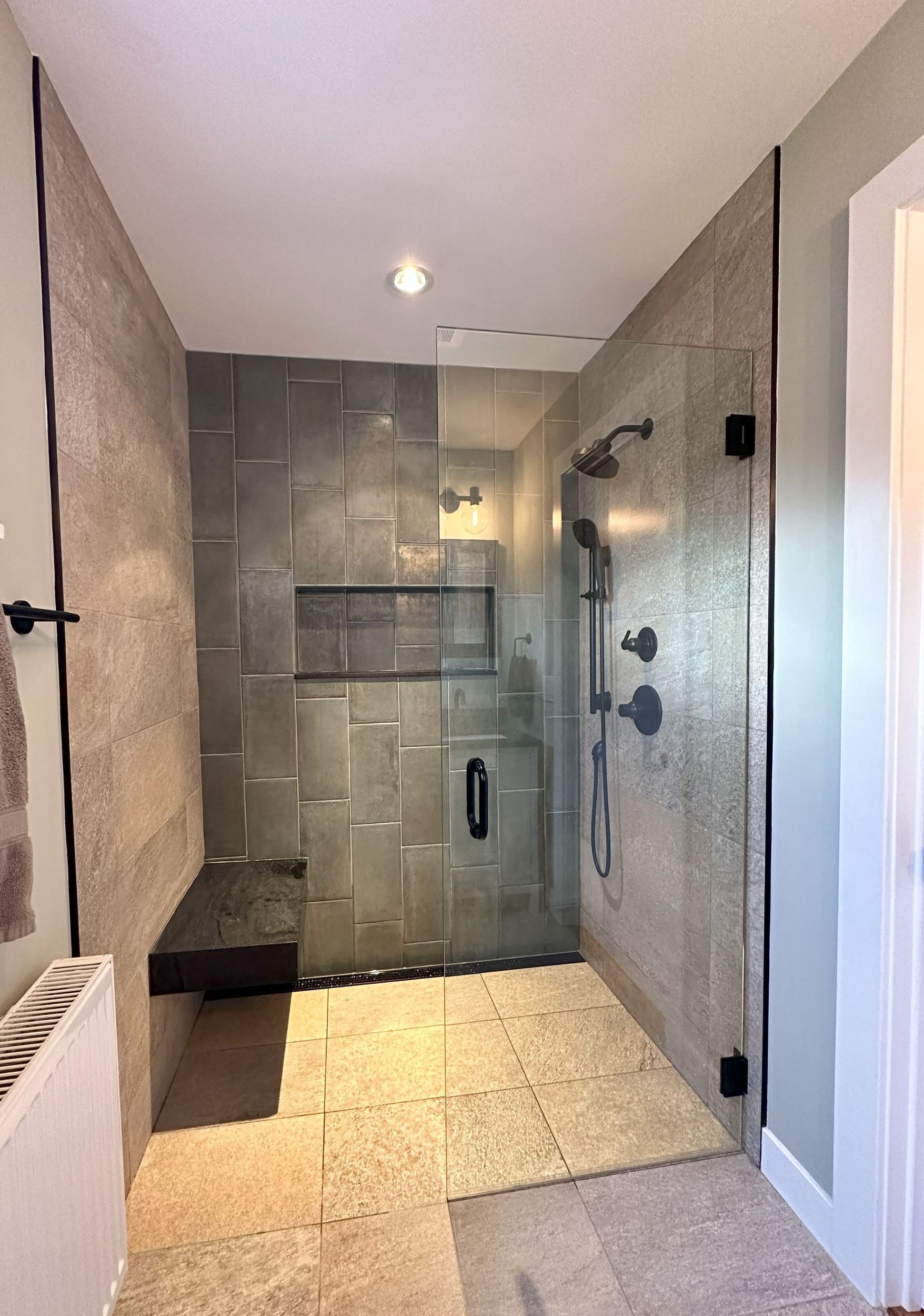 A bathroom with a walk in shower and a bench.
