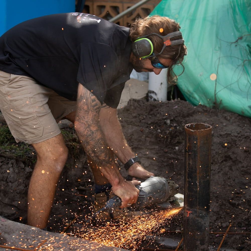 Man in Safety Gear Using a Grinder on Metal Pillar — Workwise Clothing Forster in Taree, NSW