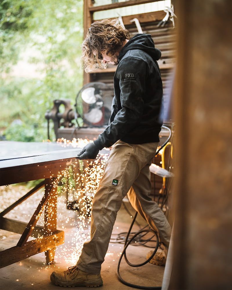Person in Work Clothes Grinding Metal, Sparks Flying, Outdoors — Workwise Clothing Forster in Forster, NSW