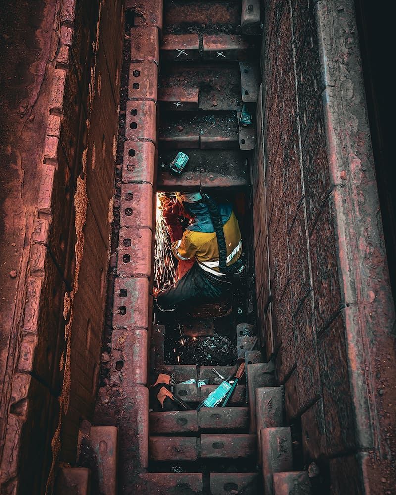 Person in a Yellow and Blue Striped Shirt Sits in a Narrow, Dark Stairwell — Workwise Clothing Forster in Wingham, NSW