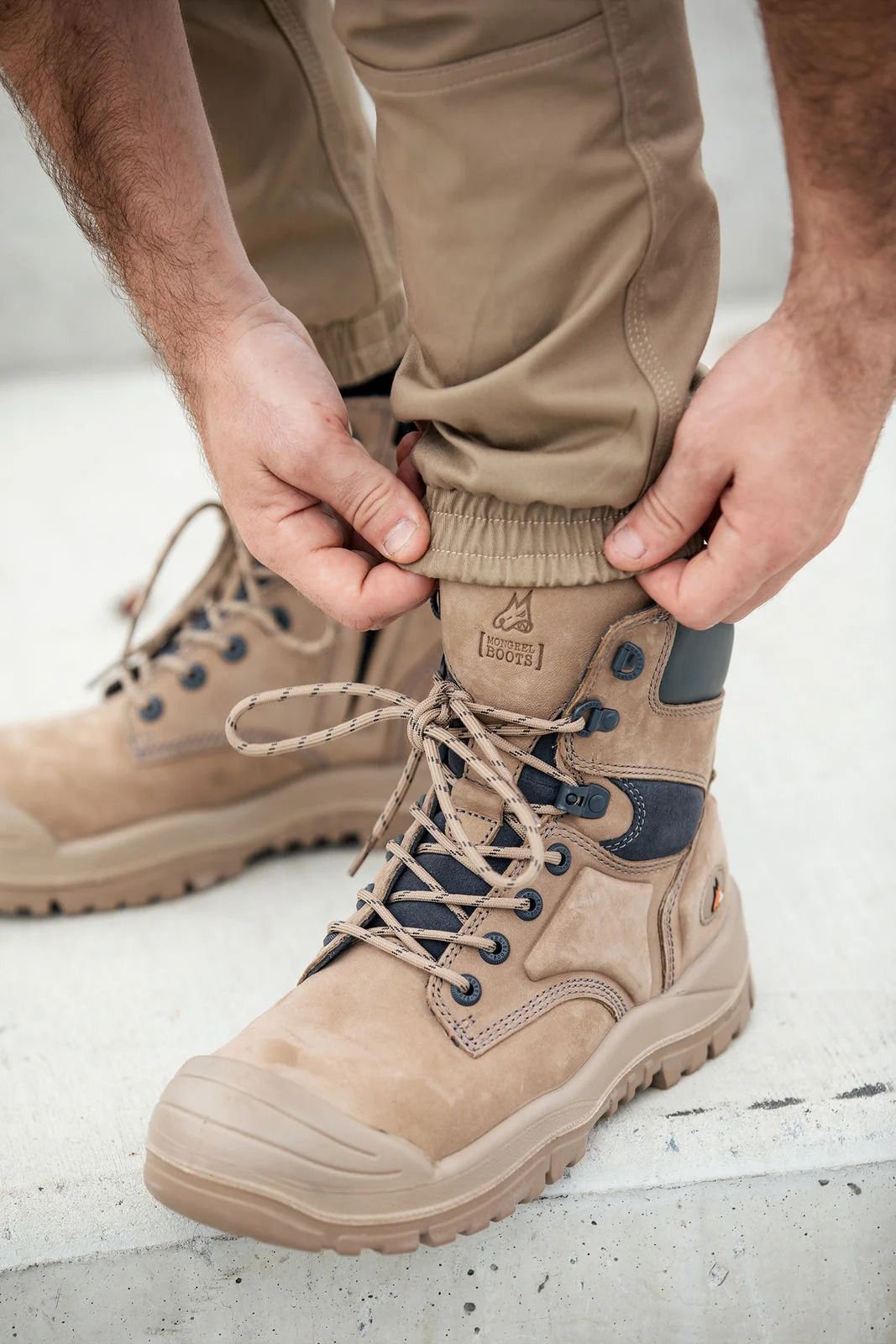 Man adjusting tan work pants over tan work boots — Workwise Clothing Forster in Forster, NSW