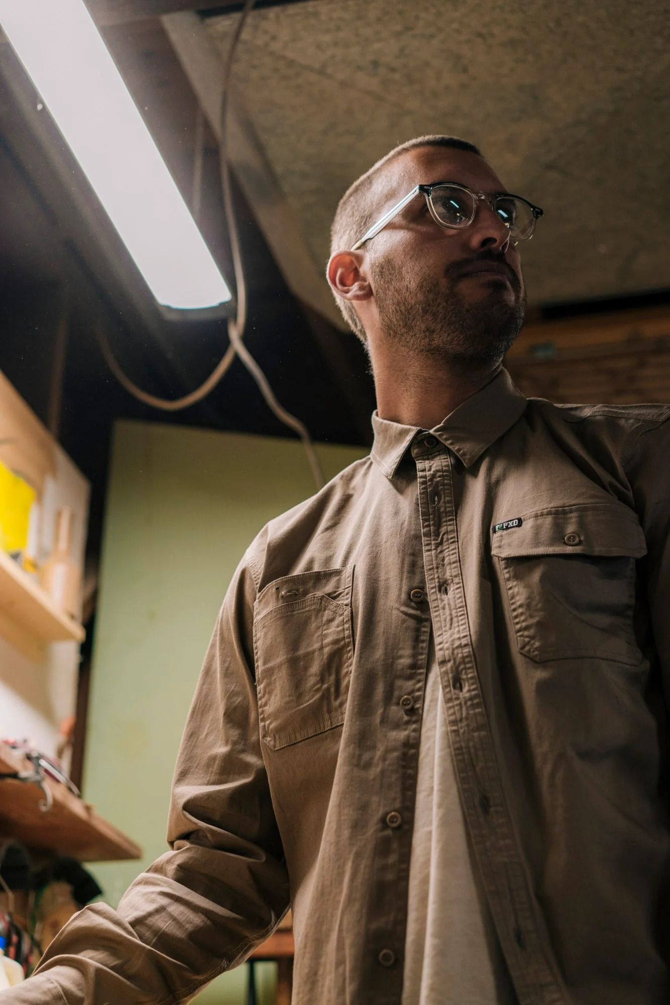 Man in glasses and brown shirt, looking upwards in a workshop — Workwise Clothing Forster in Forster, NSW