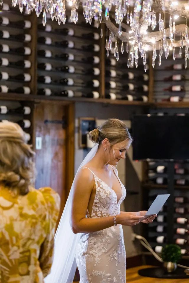 A bride in a wedding dress is reading a letter from her groom.