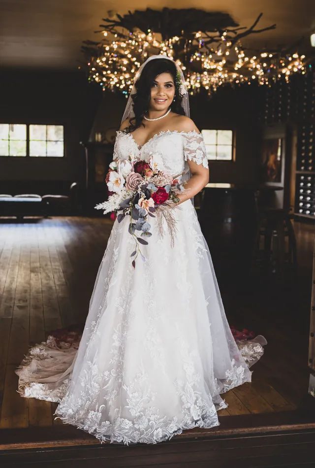 The bride is wearing a white wedding dress and holding a bouquet of flowers.